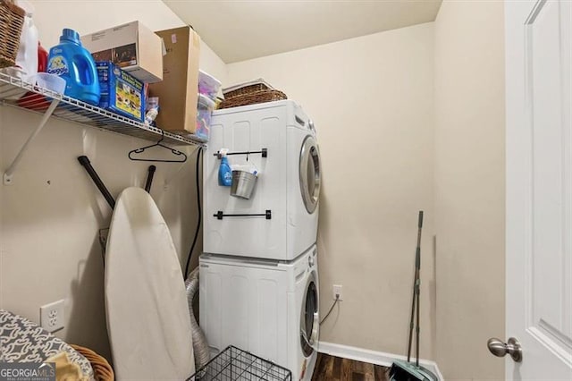 laundry area featuring laundry area, stacked washer / dryer, baseboards, and wood finished floors