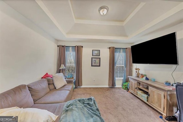 living area featuring a tray ceiling, baseboards, light colored carpet, and a healthy amount of sunlight