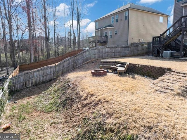 view of yard featuring stairs, cooling unit, a fire pit, and a fenced backyard