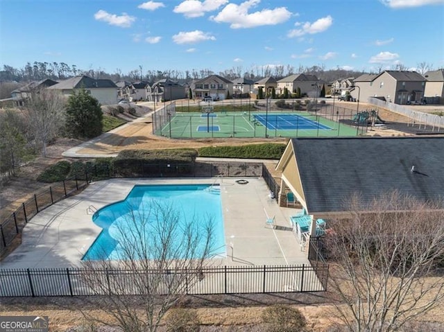 community pool featuring a residential view, a tennis court, and fence