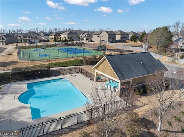 pool with a tennis court, fence, a residential view, and a patio