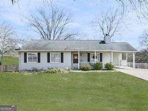 view of front of home featuring driveway, a carport, a porch, and a front lawn