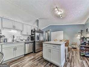 kitchen with a kitchen island, light countertops, appliances with stainless steel finishes, wood finished floors, and a sink