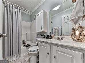 bathroom featuring crown molding, toilet, tile patterned floors, vanity, and shower / bathtub combination with curtain