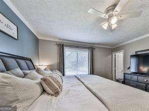 bedroom with a textured ceiling, ceiling fan, and crown molding