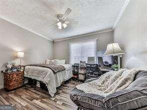 bedroom featuring a ceiling fan, wood finished floors, and ornamental molding