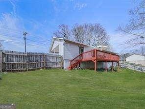 rear view of property featuring a yard, a wooden deck, and a fenced backyard