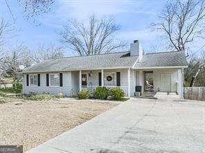 view of front of house with covered porch, driveway, and a chimney