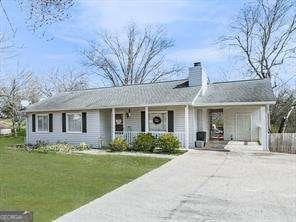 view of front of home featuring an attached carport, driveway, covered porch, a chimney, and a front lawn