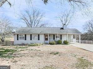 single story home featuring an attached carport, a porch, driveway, and fence