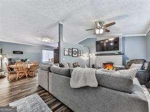 living area featuring a fireplace, dark wood-type flooring, and ceiling fan