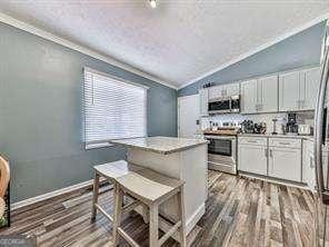 kitchen with light countertops, vaulted ceiling, appliances with stainless steel finishes, wood finished floors, and white cabinetry