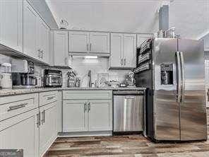 kitchen featuring dark wood-type flooring, a sink, backsplash, stainless steel appliances, and white cabinets