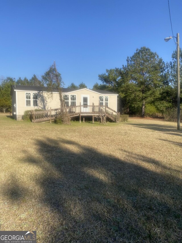 rear view of property featuring a deck and a lawn