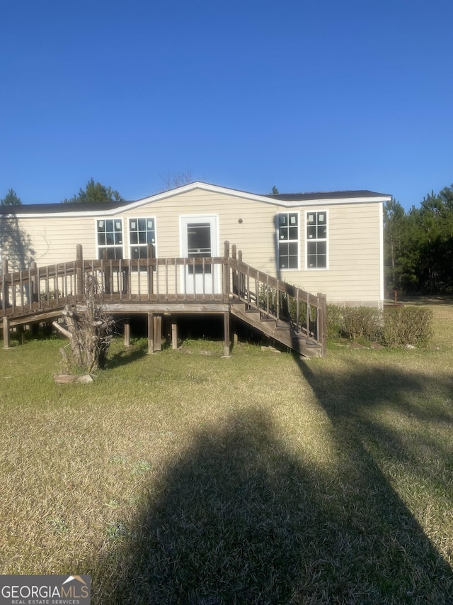 rear view of house featuring a yard and a deck