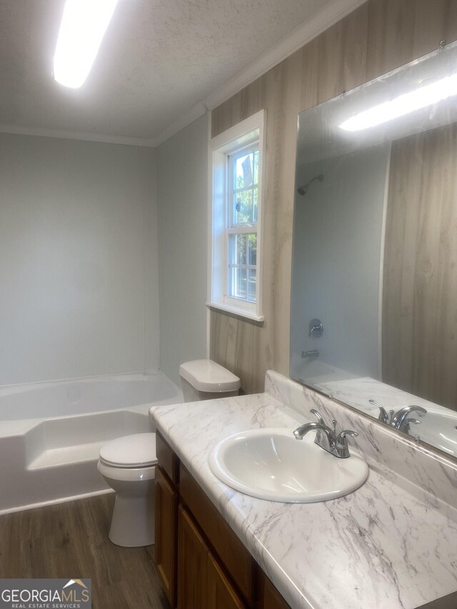 full bathroom featuring toilet, wood finished floors,  shower combination, crown molding, and vanity