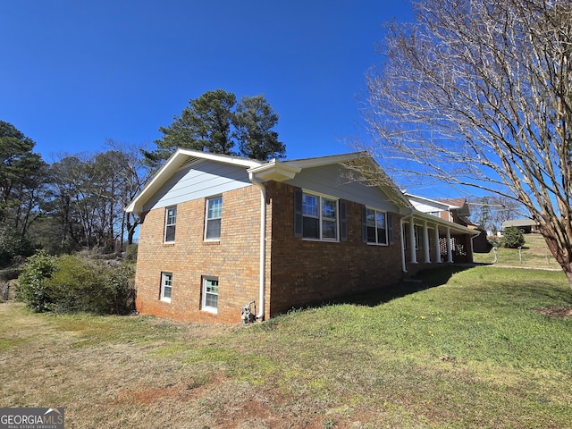 view of side of property featuring brick siding and a lawn