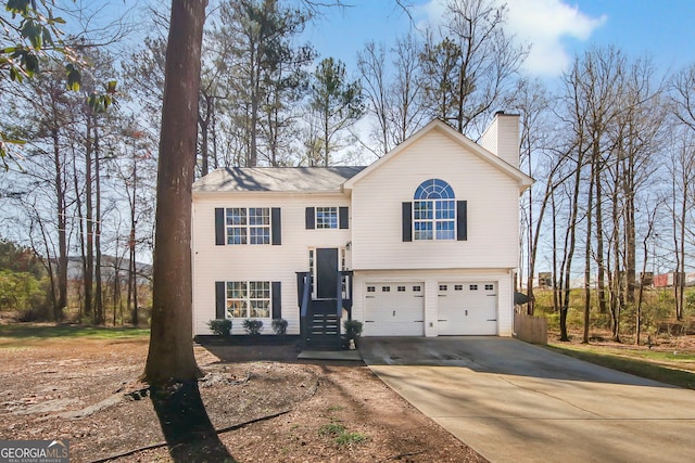 split foyer home featuring an attached garage, concrete driveway, and a chimney