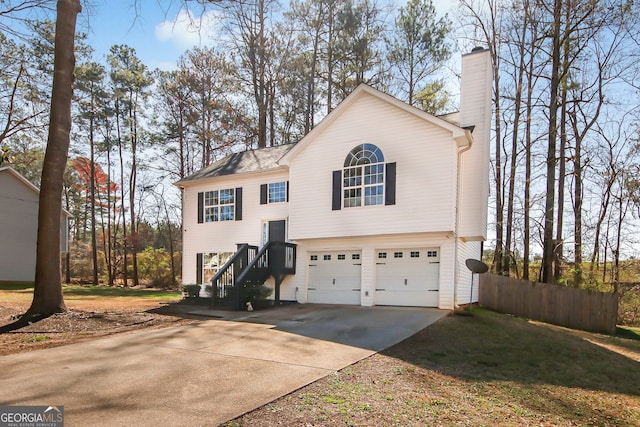 view of front of property featuring concrete driveway, fence, a garage, and a chimney