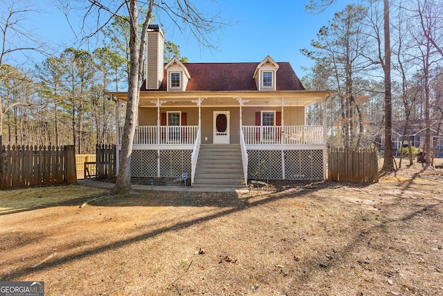 view of front of home with stairway, a porch, a chimney, and fence