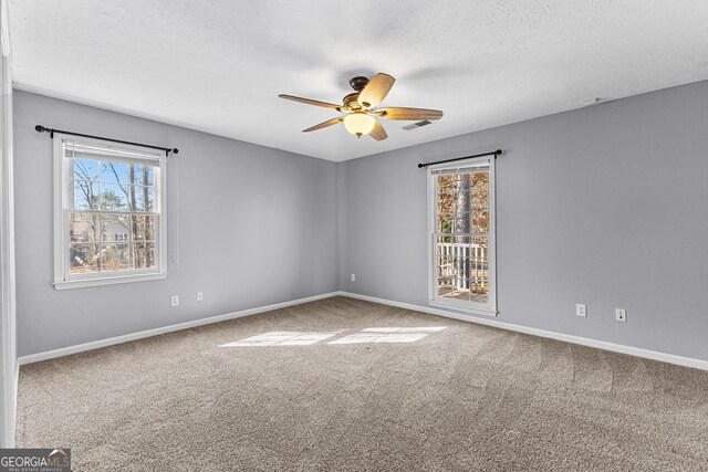 carpeted empty room with visible vents, baseboards, a textured ceiling, and ceiling fan