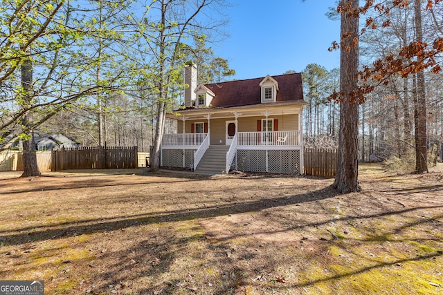 cape cod-style house featuring a porch, a chimney, stairs, and fence