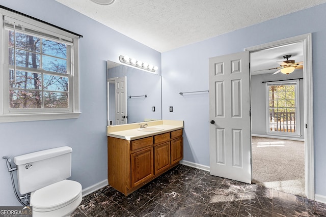 bathroom featuring baseboards, toilet, vanity, and a textured ceiling