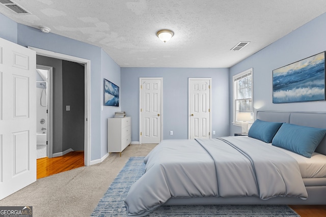 carpeted bedroom featuring visible vents, multiple closets, a textured ceiling, and baseboards