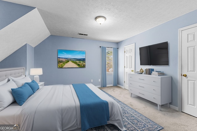 bedroom featuring baseboards, visible vents, vaulted ceiling, a textured ceiling, and light colored carpet