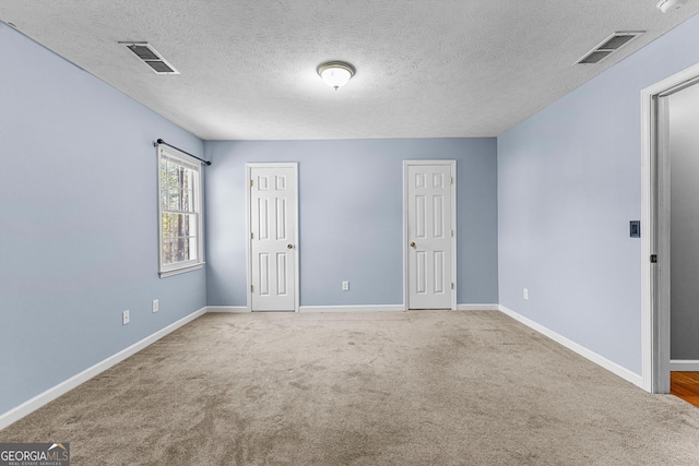 unfurnished bedroom with visible vents, a textured ceiling, baseboards, and carpet floors