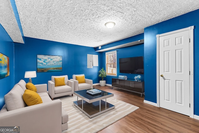 living area with wood finished floors, baseboards, and a textured ceiling