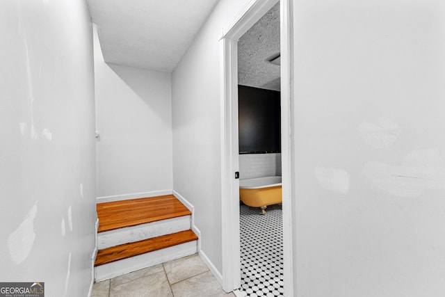 stairs featuring baseboards and a textured ceiling