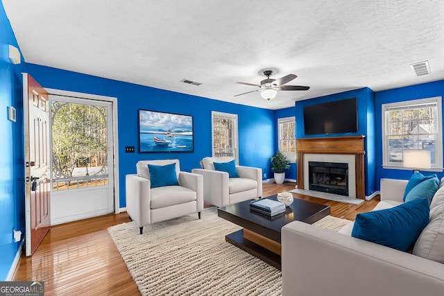 living area featuring visible vents, plenty of natural light, and wood finished floors