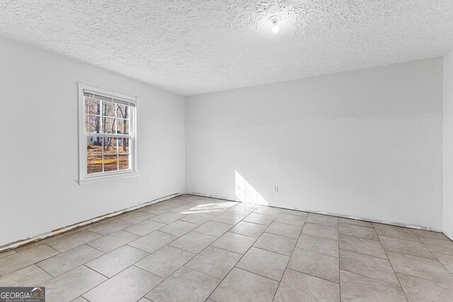 empty room with light tile patterned floors and a textured ceiling