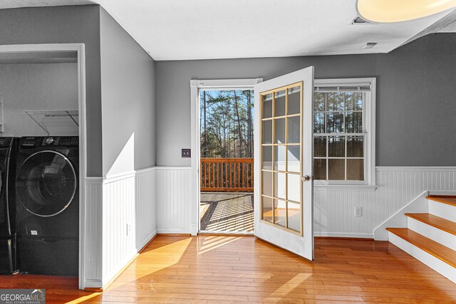 doorway to outside featuring stairway, washer / clothes dryer, wood-type flooring, and wainscoting