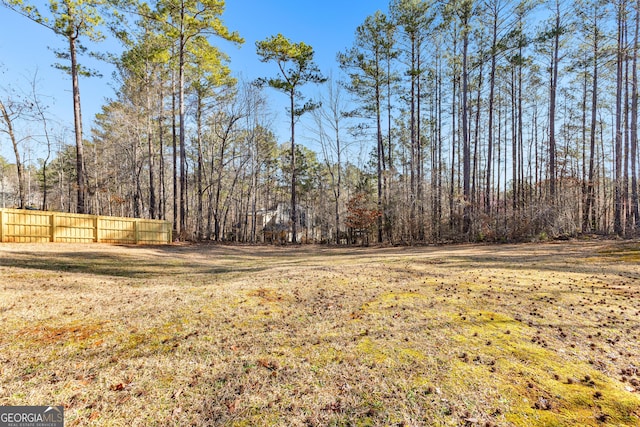 view of yard with a wooded view and fence