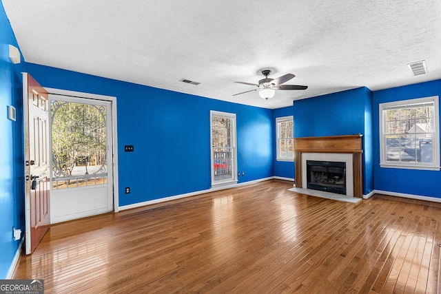 unfurnished living room featuring a wealth of natural light, visible vents, and hardwood / wood-style flooring