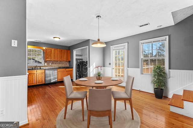 dining room with plenty of natural light, wainscoting, visible vents, and washing machine and clothes dryer