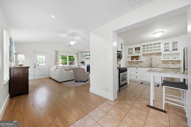 kitchen with visible vents, vaulted ceiling, decorative backsplash, white cabinets, and stainless steel appliances