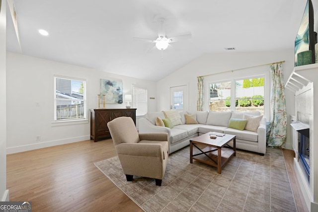 living area featuring baseboards, visible vents, light wood finished floors, lofted ceiling, and ceiling fan