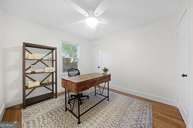 office featuring a ceiling fan, light wood-type flooring, and baseboards