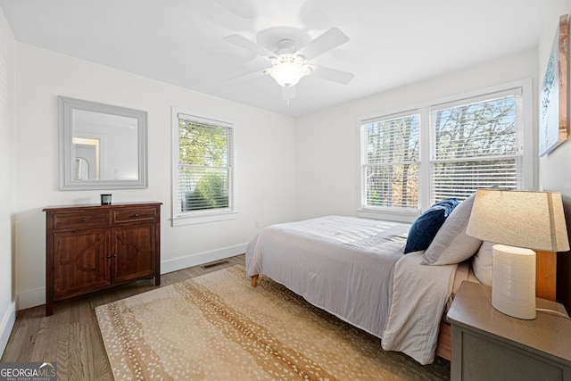 bedroom with visible vents, a ceiling fan, baseboards, and wood finished floors