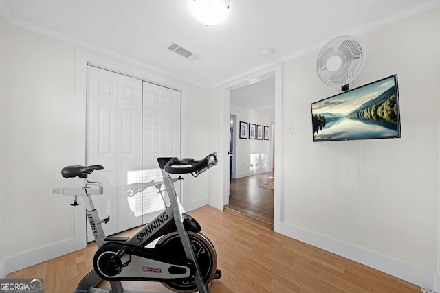 workout room featuring ornamental molding, baseboards, visible vents, and light wood-type flooring