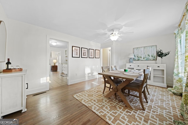 dining space with visible vents, baseboards, a ceiling fan, and wood finished floors