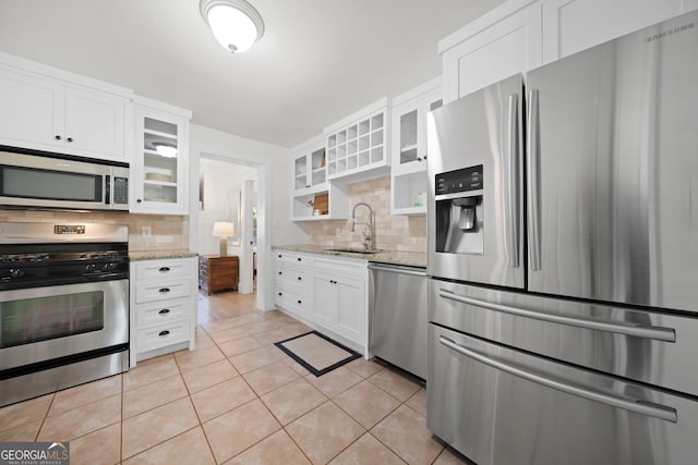 kitchen with backsplash, appliances with stainless steel finishes, white cabinetry, and a sink