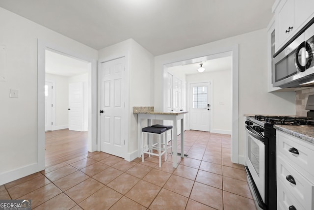 kitchen featuring light tile patterned floors, stainless steel appliances, and white cabinetry