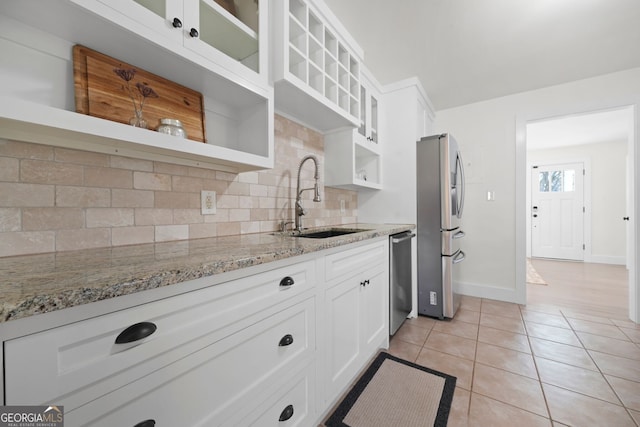 kitchen with light tile patterned floors, open shelves, stainless steel appliances, a sink, and glass insert cabinets