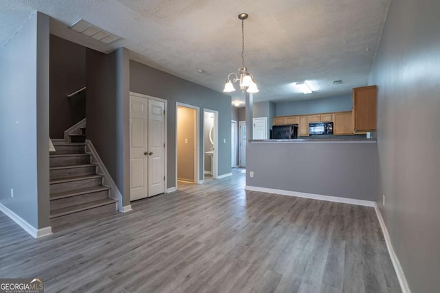 unfurnished living room with visible vents, baseboards, stairs, wood finished floors, and a textured ceiling