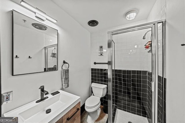 bathroom with a shower stall, toilet, and vanity