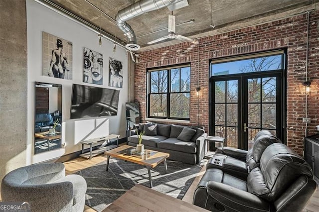 living area featuring a high ceiling, french doors, wood finished floors, and brick wall